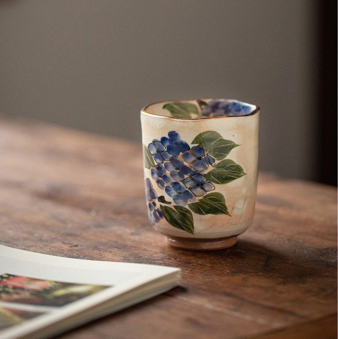 Set of hand-painted ceramic tea cups in a rustic wooden cabinet.