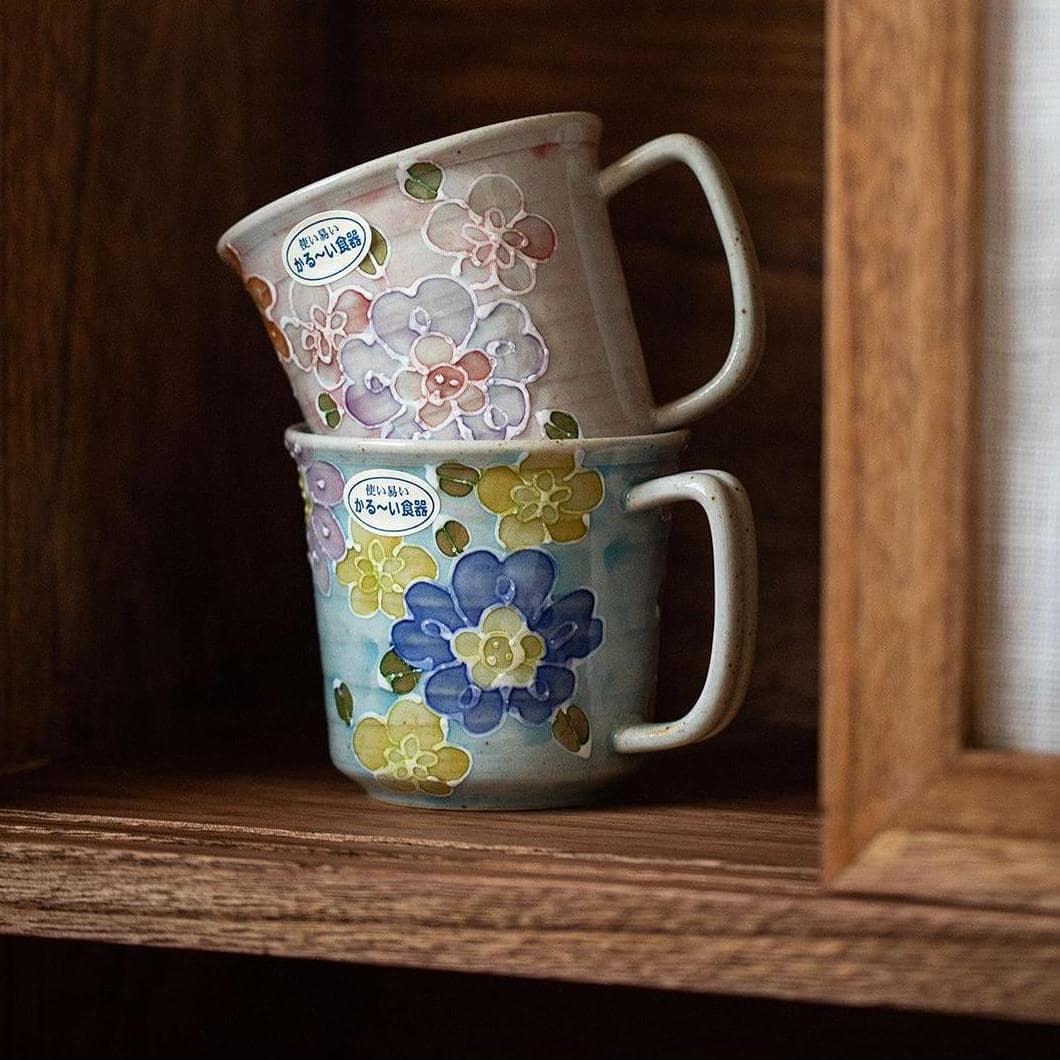 Two ceramic mugs with floral patterns on a wooden surface