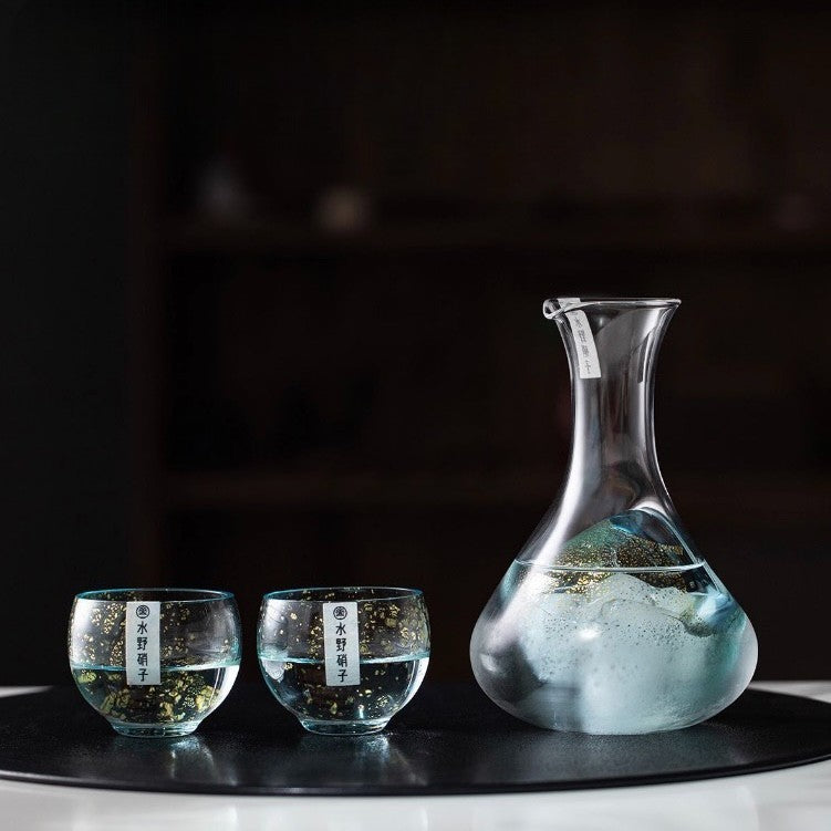 Sake set with a carafe and cups against a neutral background.