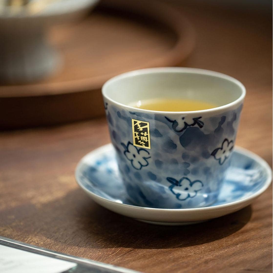 Hand holding Blue Floral Porcelain Cup filled with tea