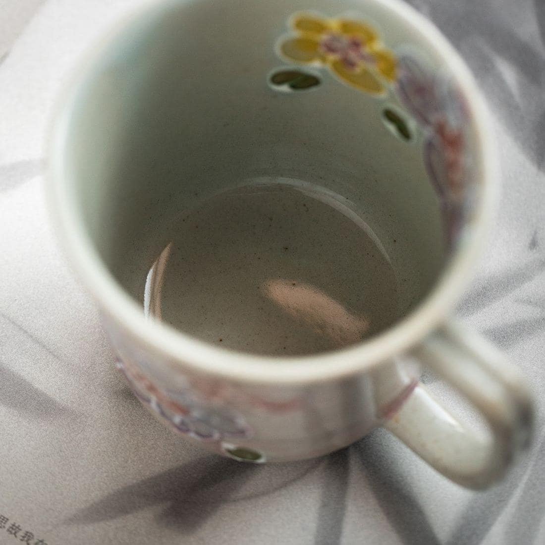 Pair of floral ceramic mugs displayed on a beige background