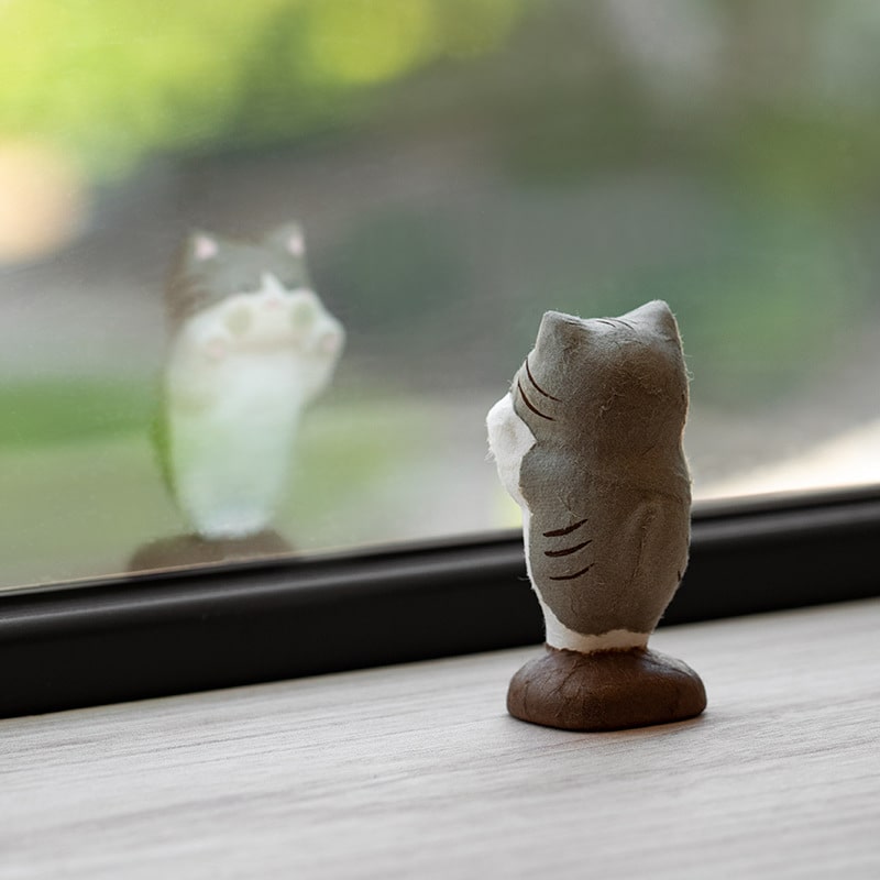 Whimsical cat figurine displayed on a windowsill