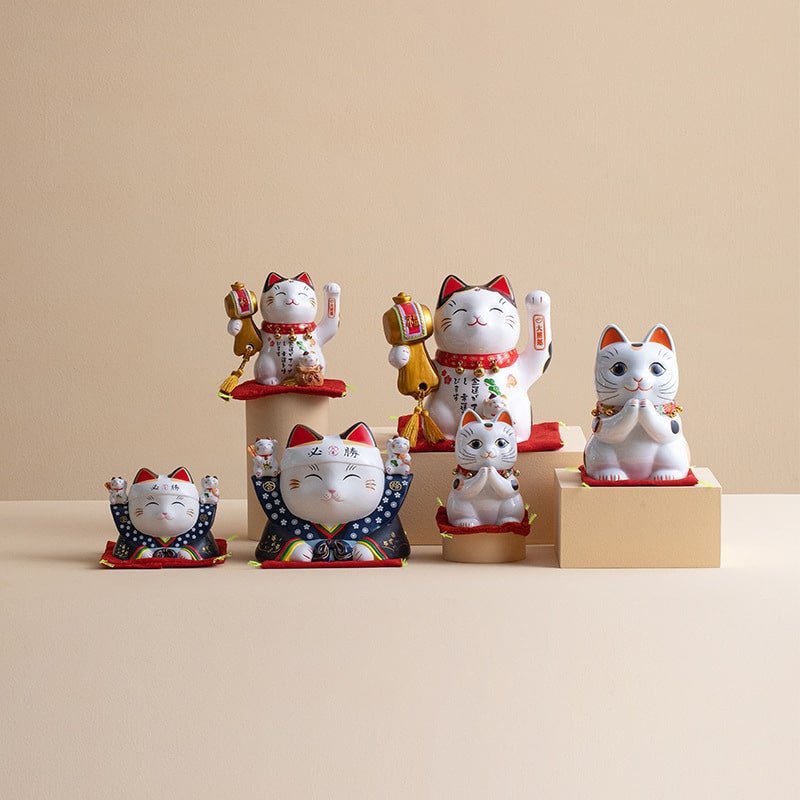 Adorable prosperity cat figurines displayed in a glass cabinet.