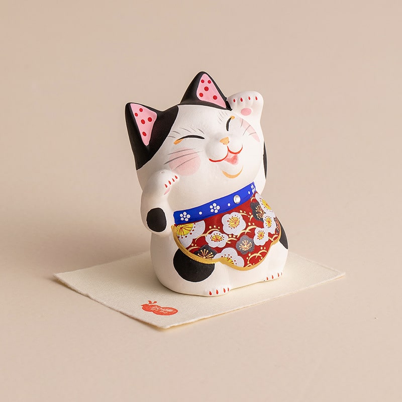 Lucky cat figurine with colorful apron on decorative mat