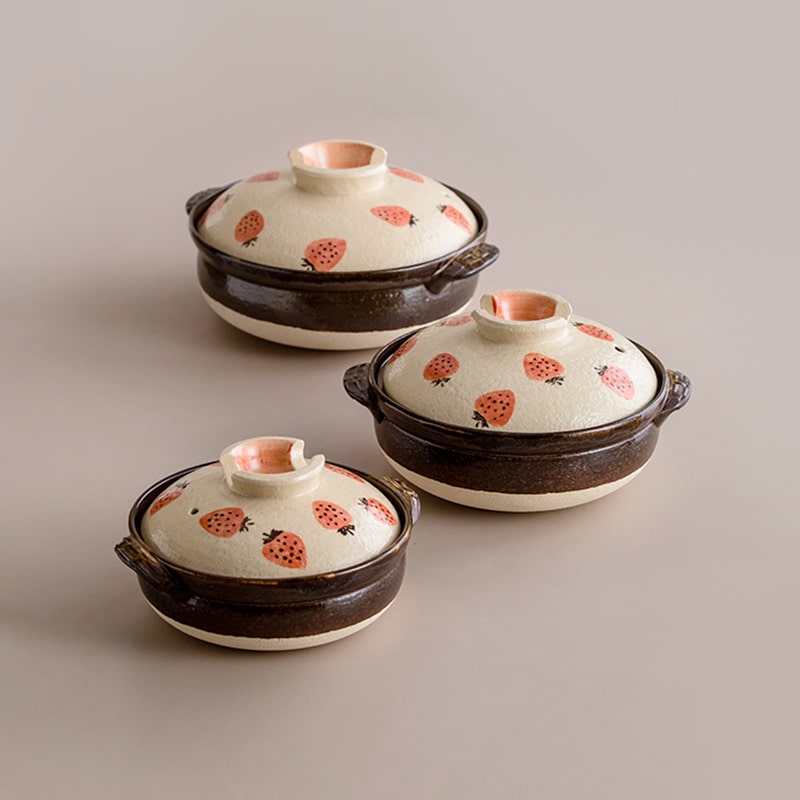 Strawberry-patterned Japanese donabe clay pot on a table.