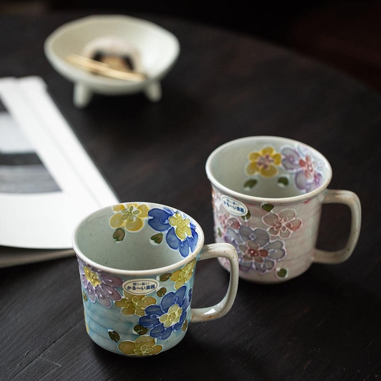 Two ceramic mugs with floral patterns on a wooden surface