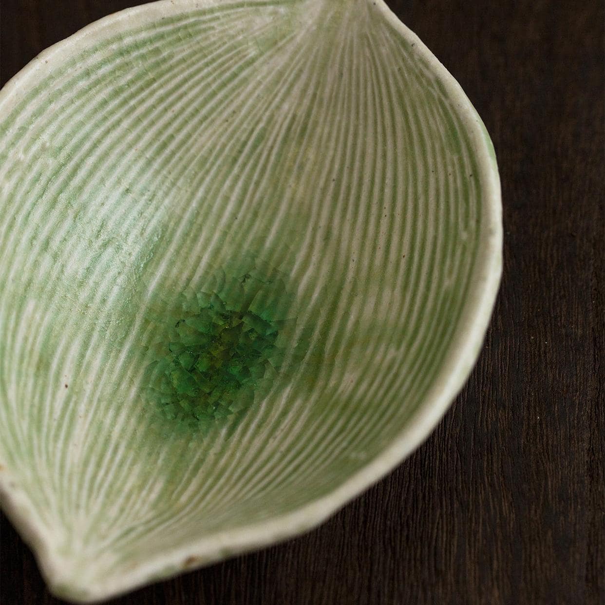 Handcrafted ceramic plate resembling a natural leaf on a wooden table