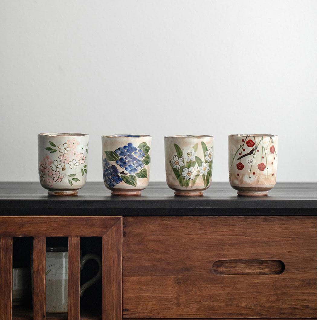 Set of hand-painted ceramic tea cups in a rustic wooden cabinet.