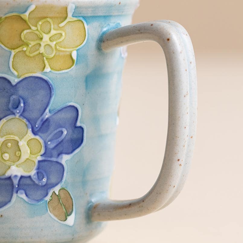 Pair of floral ceramic mugs displayed on a beige background