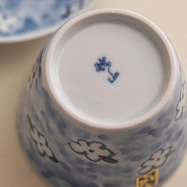 Hand holding Blue Floral Porcelain Cup filled with tea