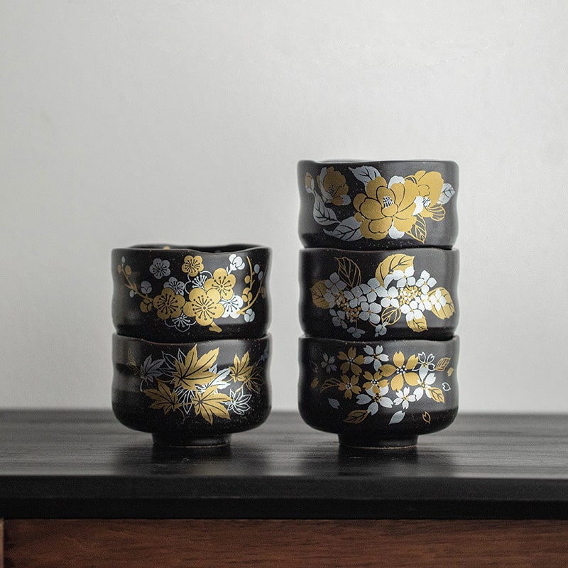 Black ceramic tea cups with gold floral designs