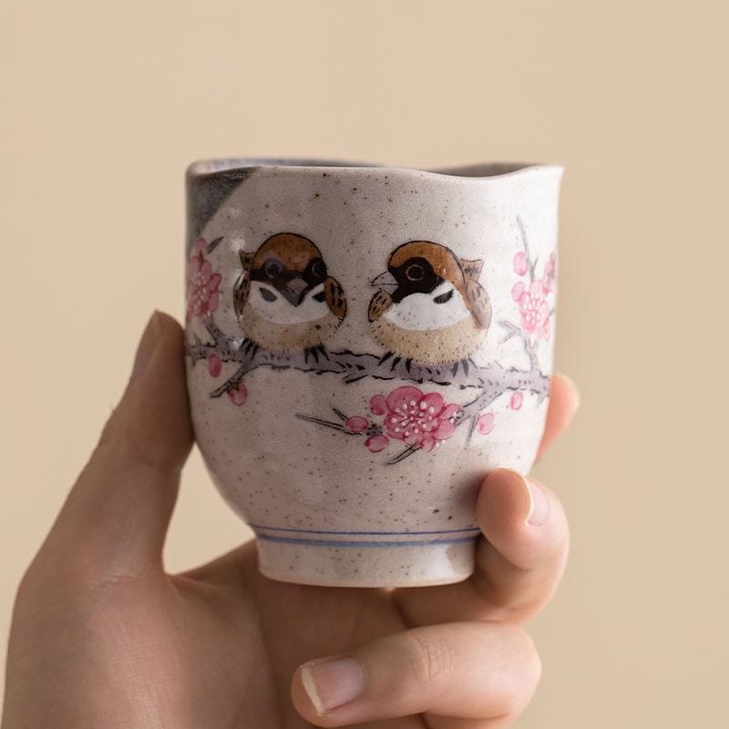 Handcrafted ceramic cup with sparrow and cherry blossom design.