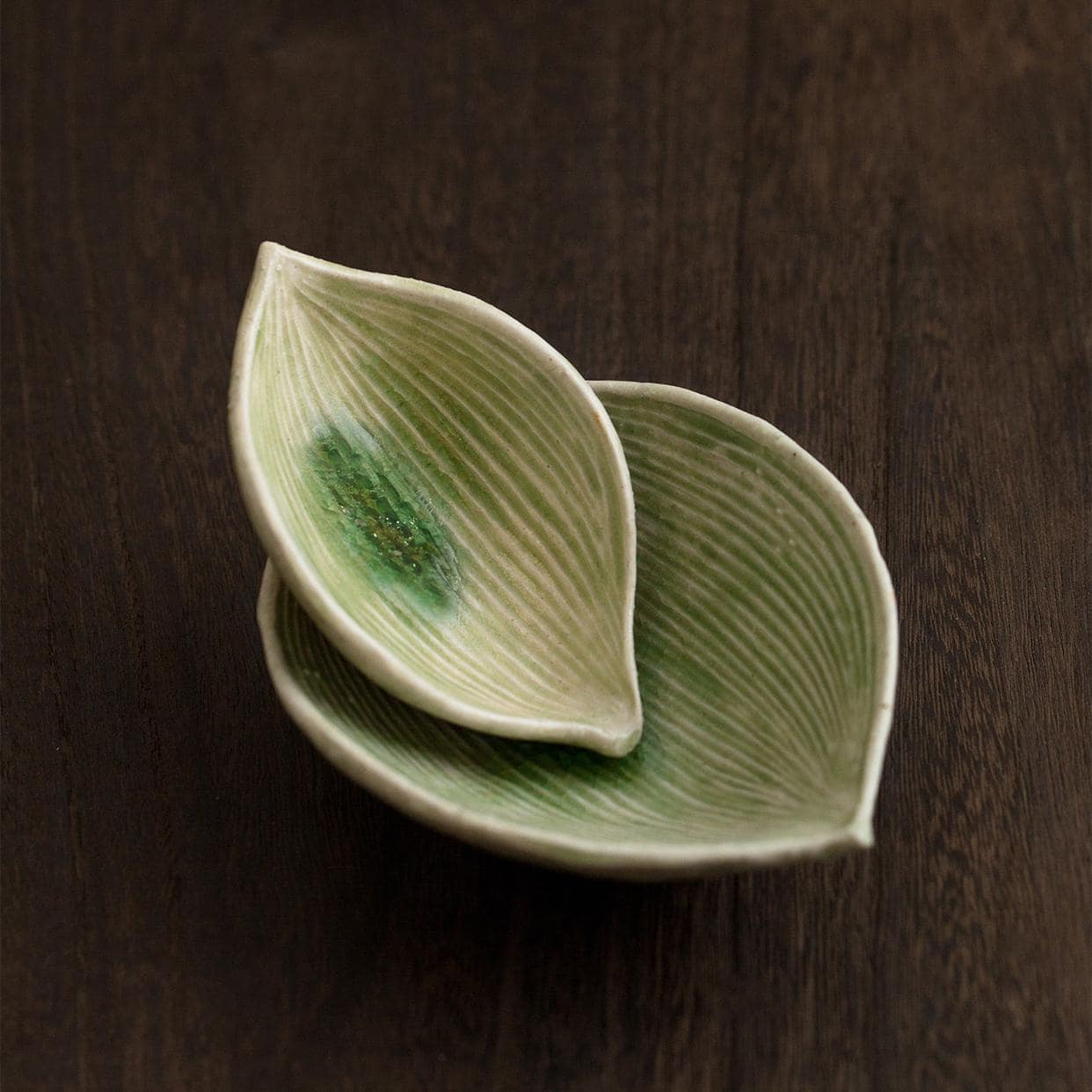 Handcrafted ceramic plate resembling a natural leaf on a wooden table