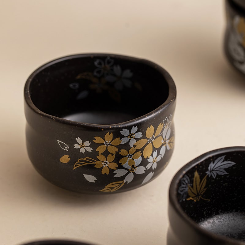 Close-up of a black ceramic cup showcasing intricate gold flower detailing