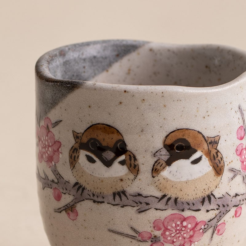 Close-up of hand-painted sparrows on a ceramic tea cup.