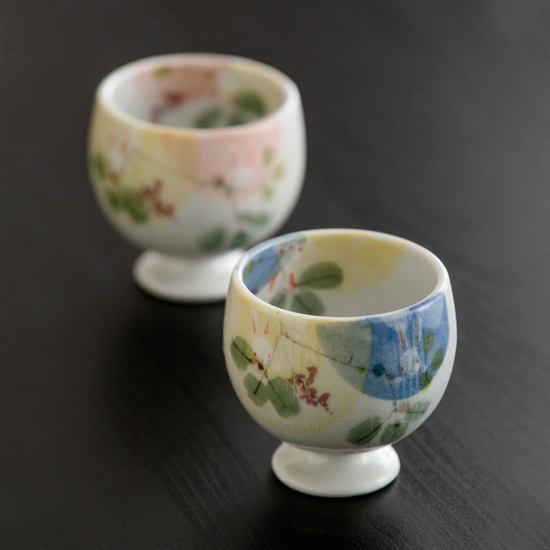 Hand holding a whimsical ceramic cup with watercolor details