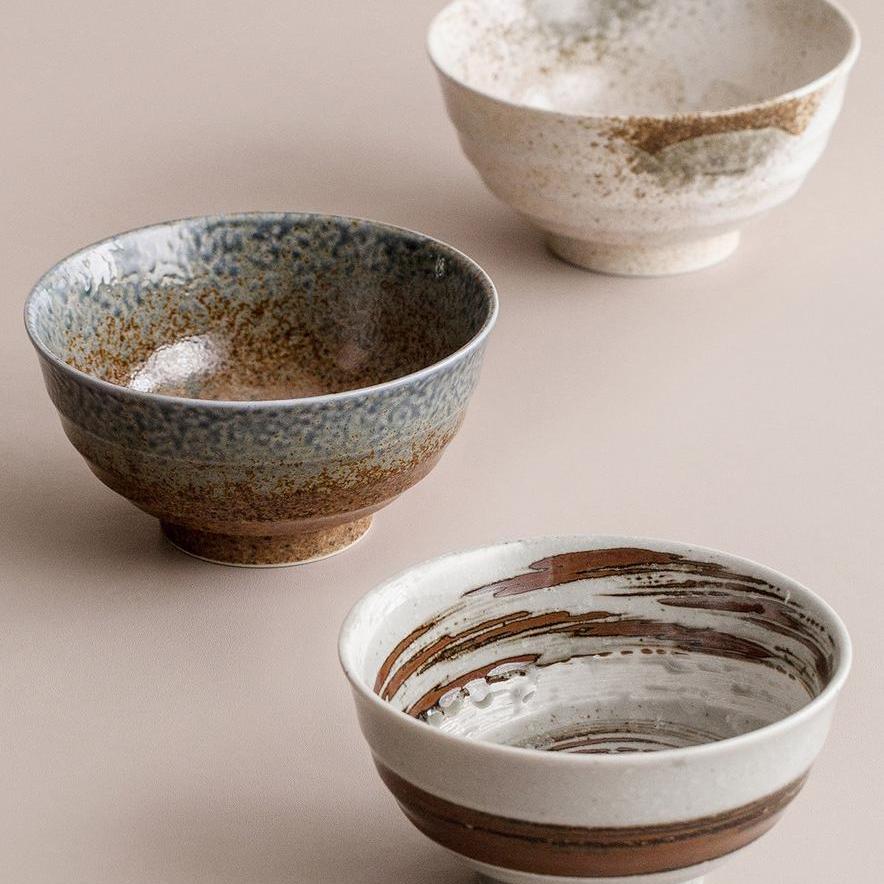 Three rustic ceramic bowls with earthy and speckled finishes