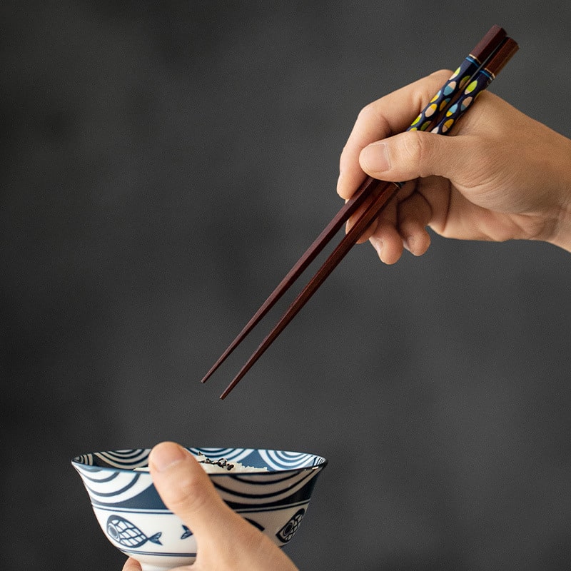 Authentic Japanese wooden chopsticks resting next to a rice bowl.