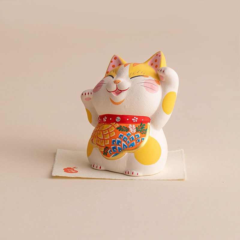 Yellow spotted Lucky Cat waving paw on display