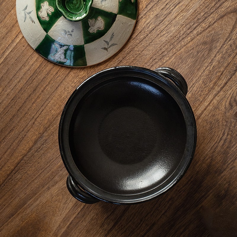 Close-up of hand-painted green and white rabbit design on Oribe pot