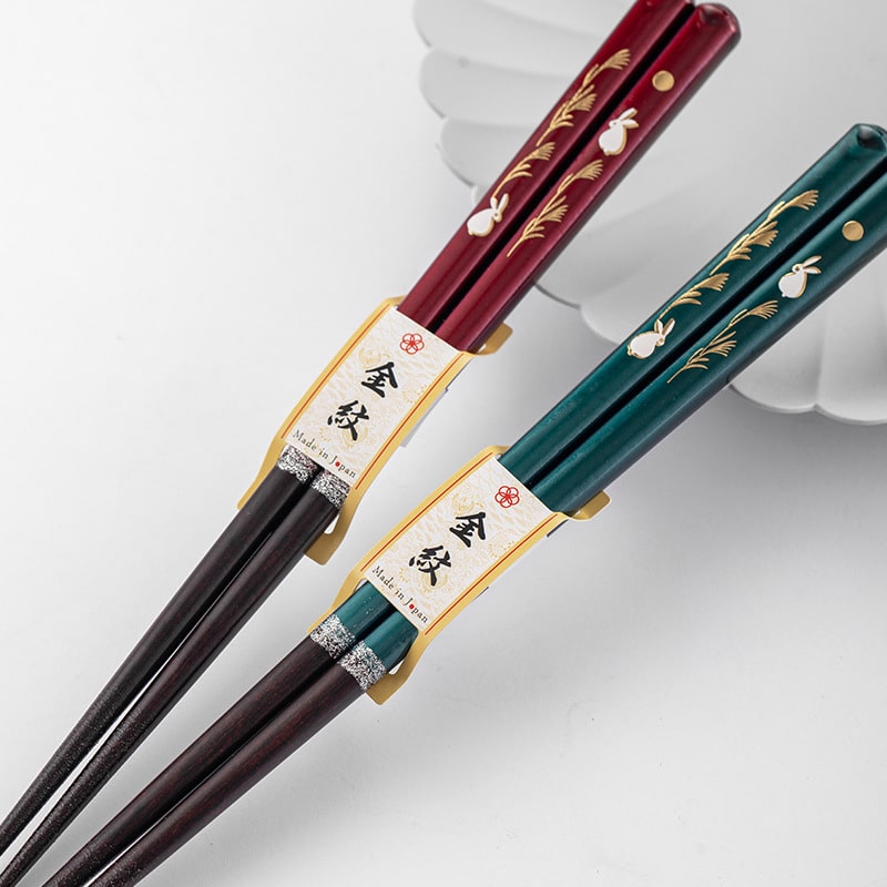 Red and green lacquered chopsticks showcasing intricate motifs.