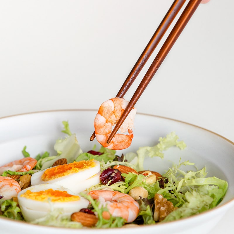 Close-up of reusable wooden chopsticks picking shrimp