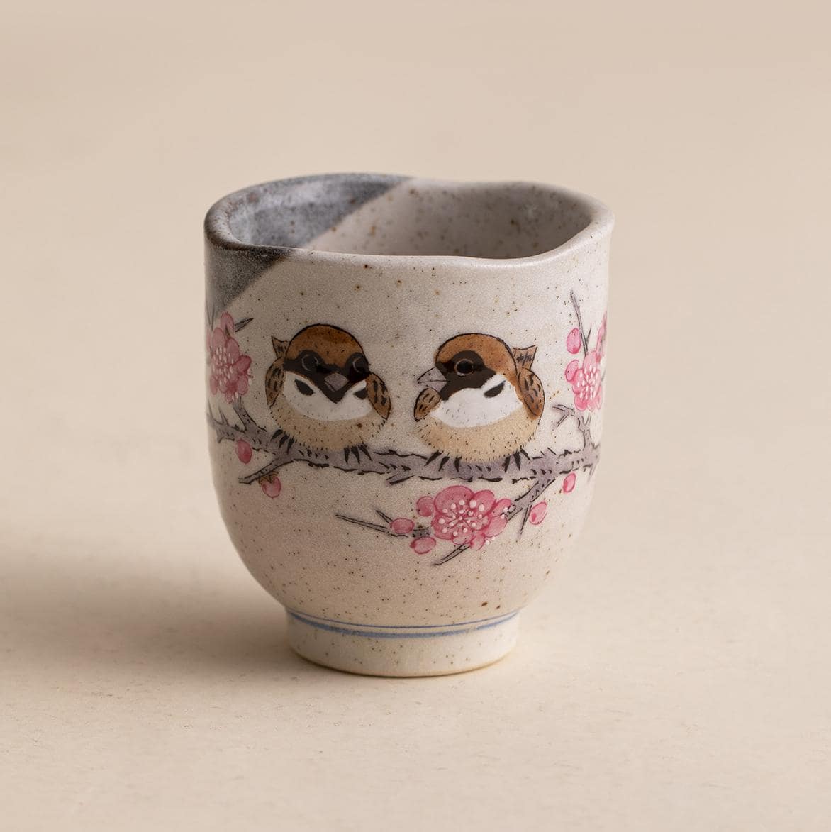 Handcrafted ceramic cup with sparrow and cherry blossom design.