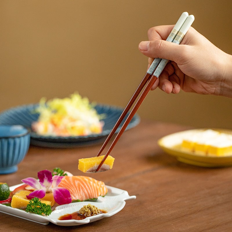 Elegant wooden chopsticks set paired with sushi and wooden rests.