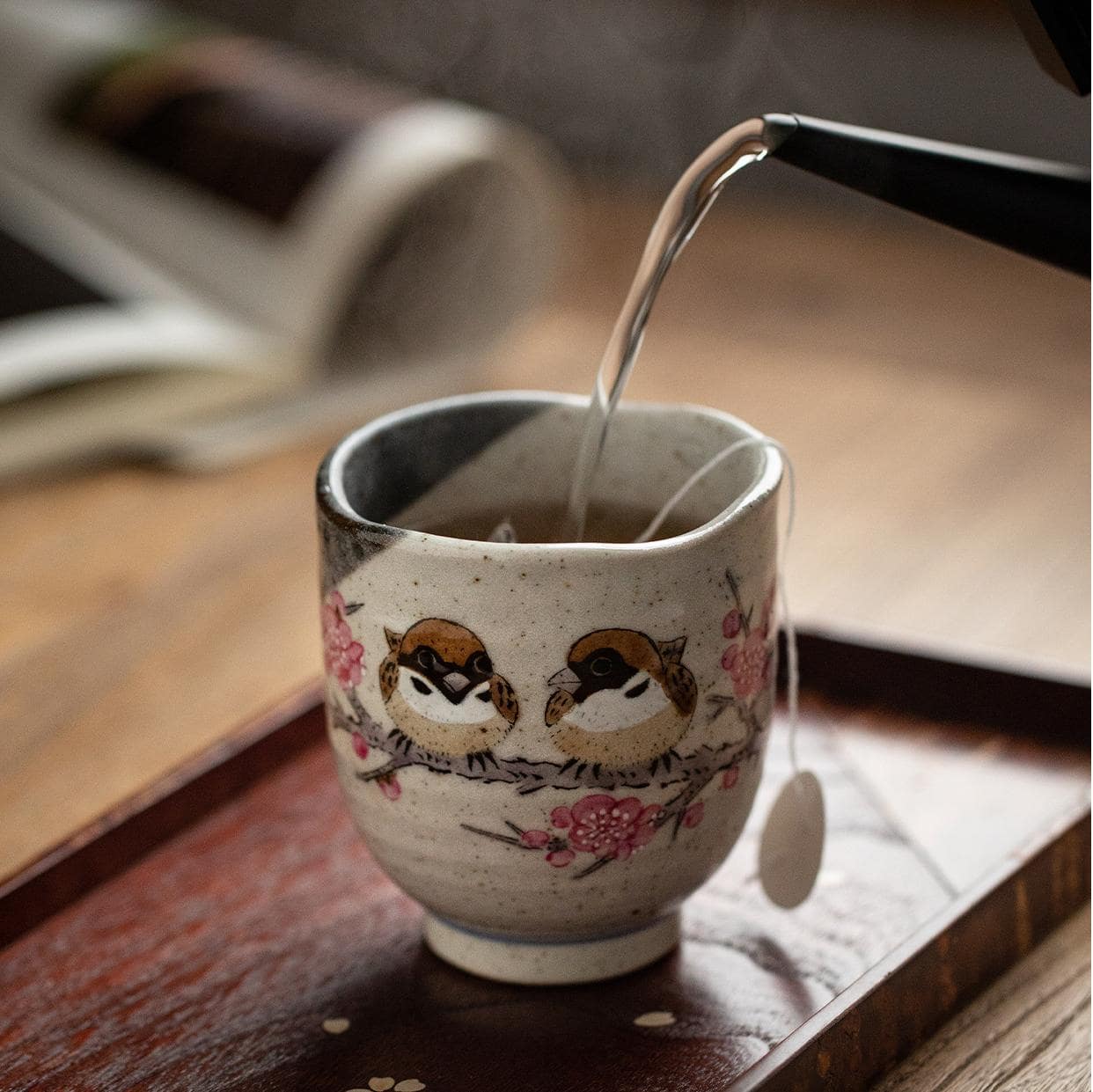 Speckled ceramic cup with cherry blossom artwork.