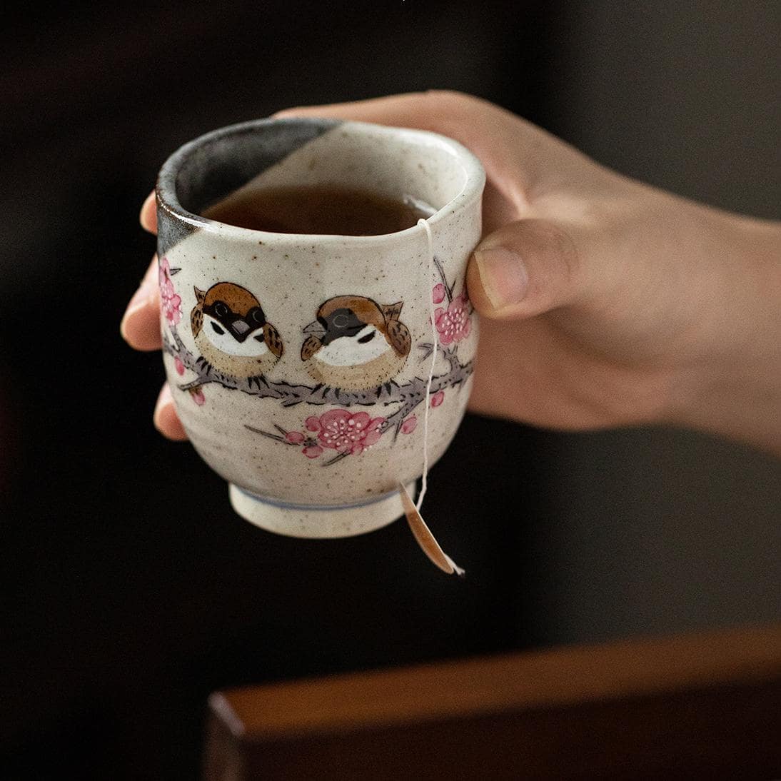 Unique sparrow-themed ceramic cup on a wooden tray.