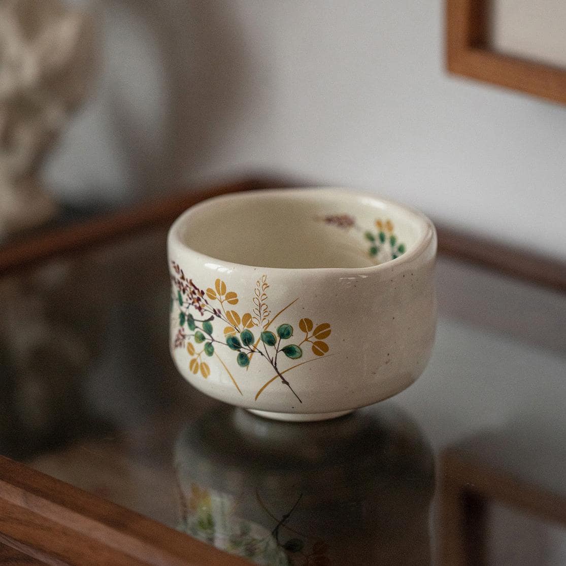 Set of white ceramic cups with colorful floral artwork displayed on wooden shelves