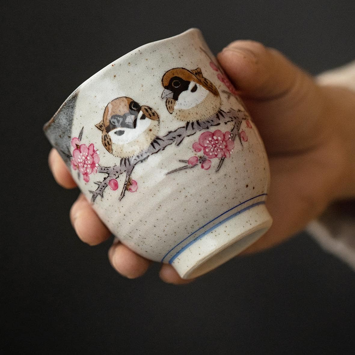 Handcrafted ceramic cup with sparrow and cherry blossom design.