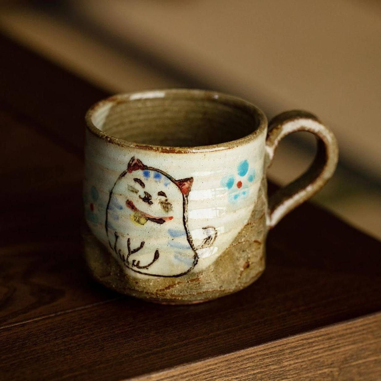 Collection of whimsical hand-painted cups with animal designs on a shelf.