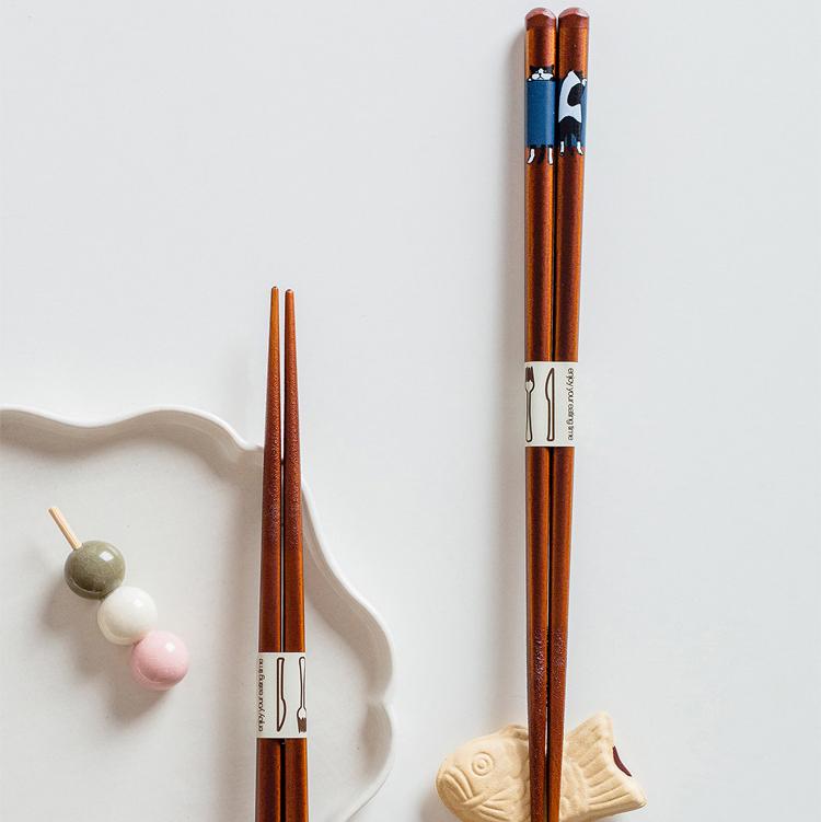 Cat-themed wooden chopsticks on white ceramic plate