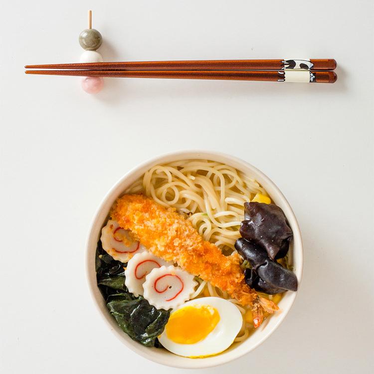 Hand holding Japanese chopsticks with cat designs