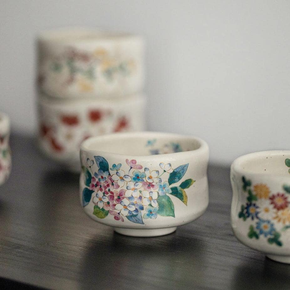 Close-up of a black ceramic cup showcasing intricate gold flower detailing