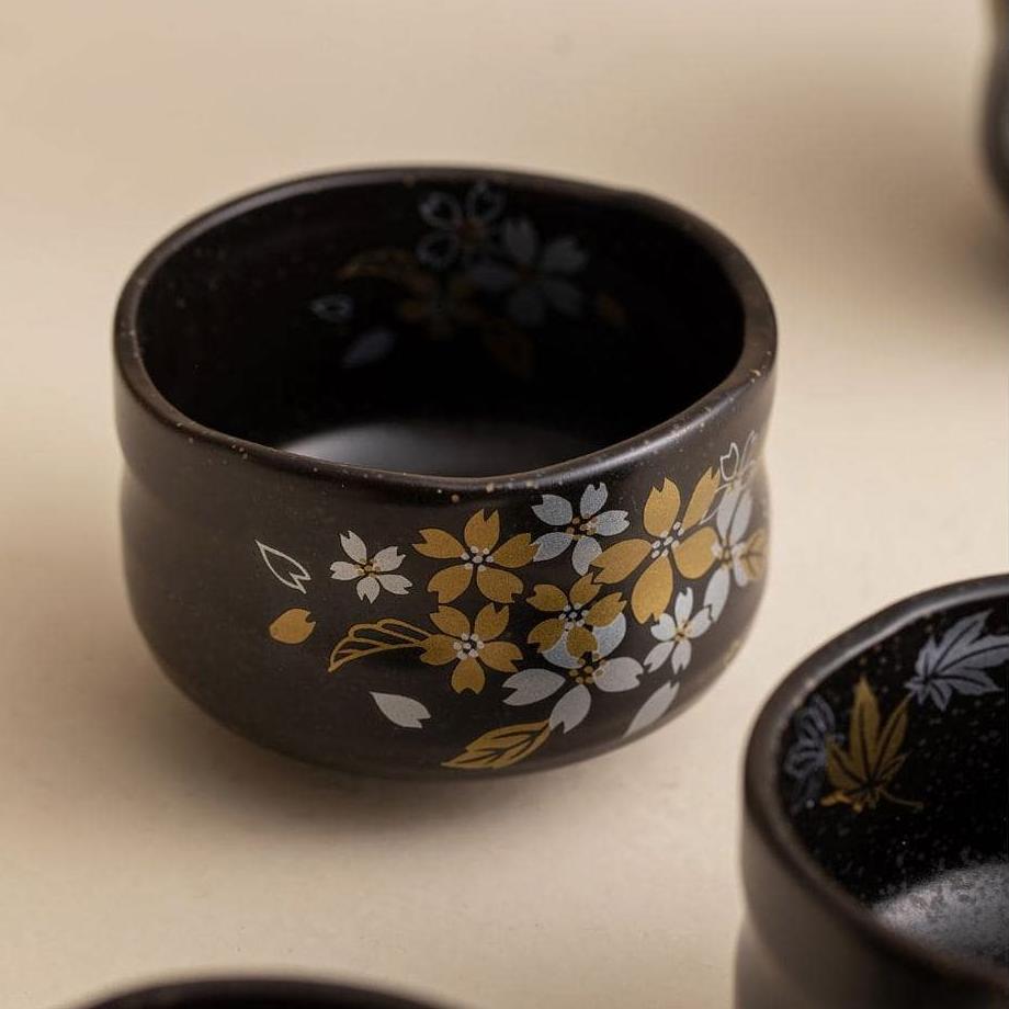 Set of white ceramic cups with colorful floral artwork displayed on wooden shelves