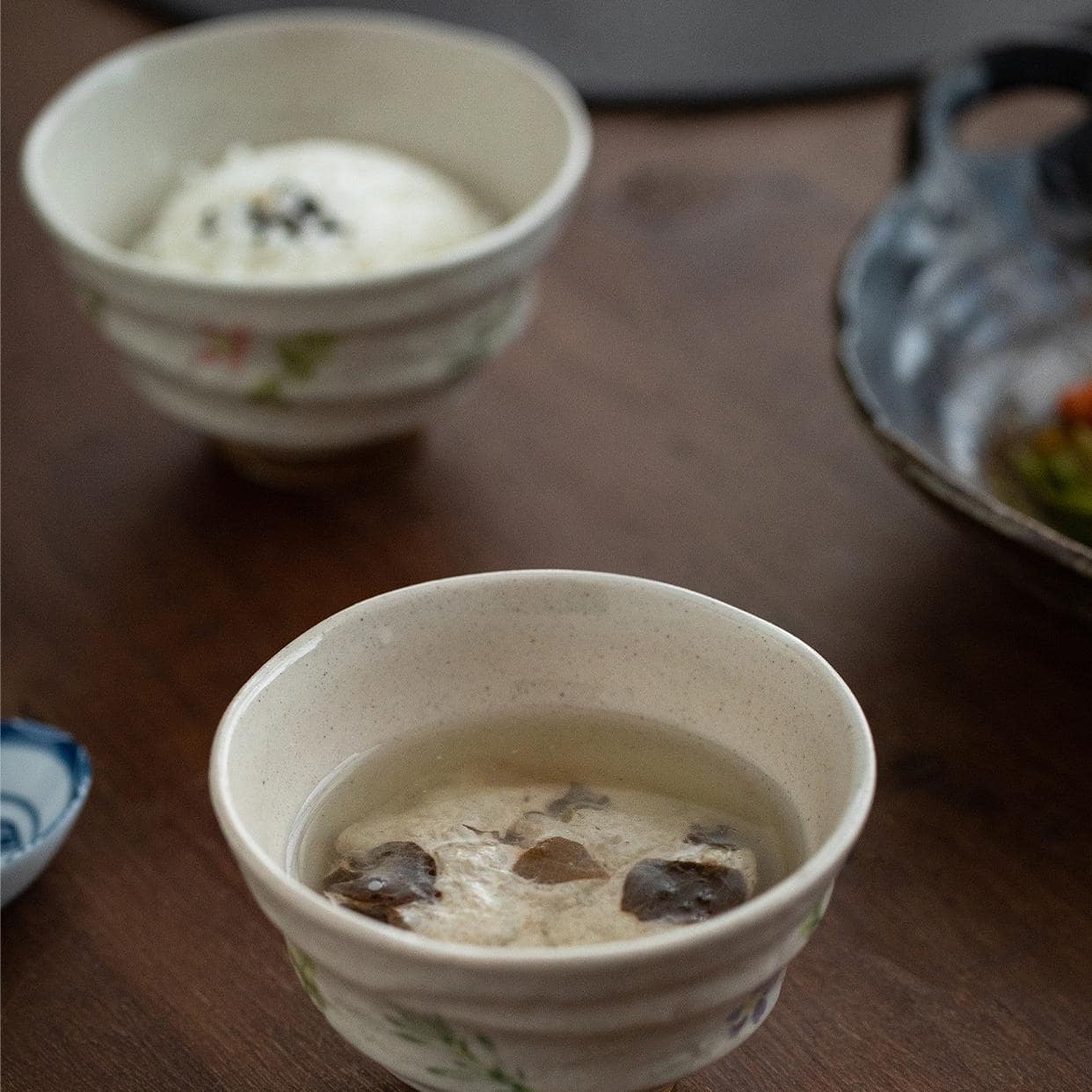 Stack of floral ceramic bowls on a table with chopsticks