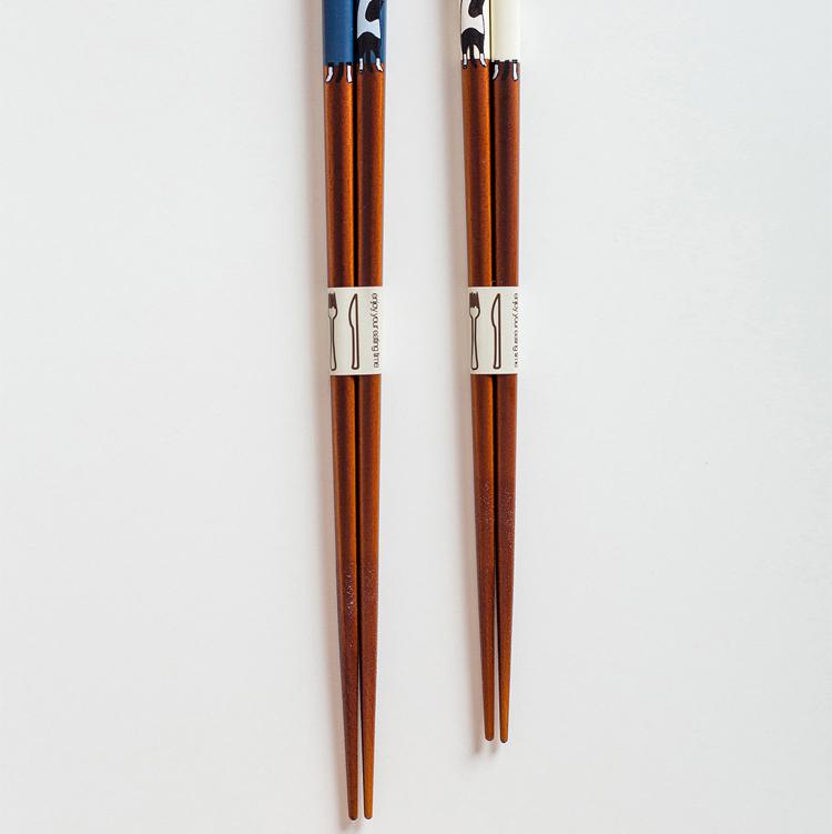 Hand holding Japanese chopsticks with cat designs