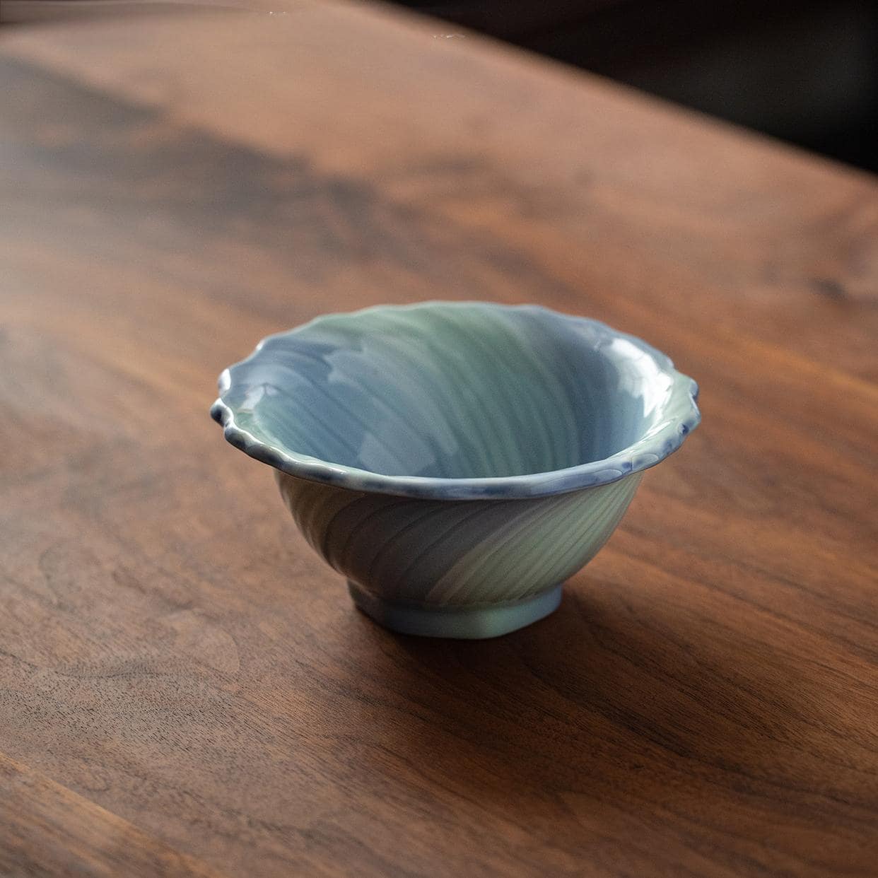 Elegant Japanese ceramic bowl filled with cold dishes on a wooden table.