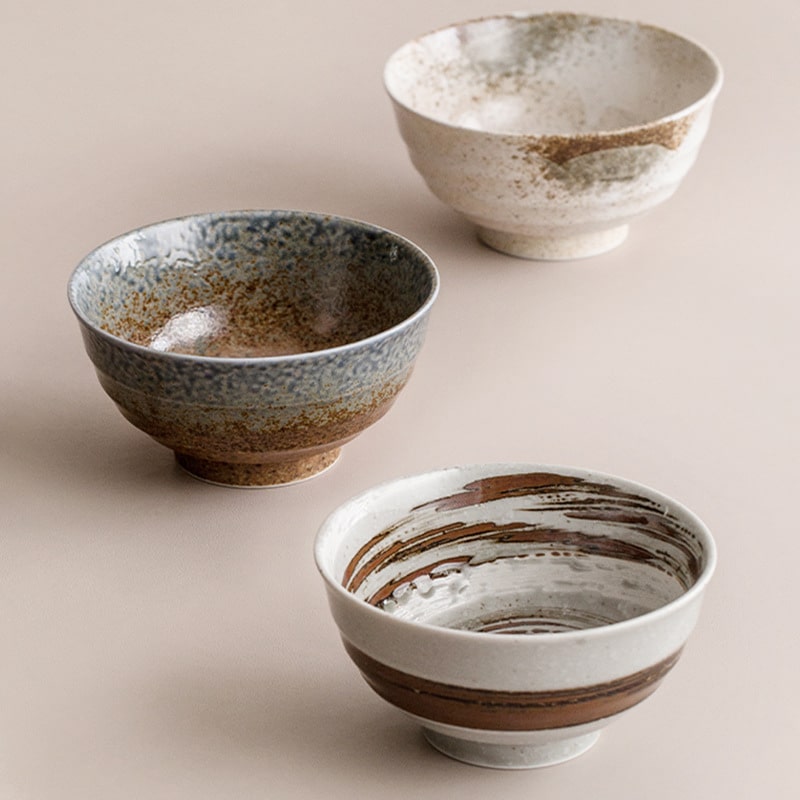 Three rustic ceramic bowls with earthy and speckled finishes