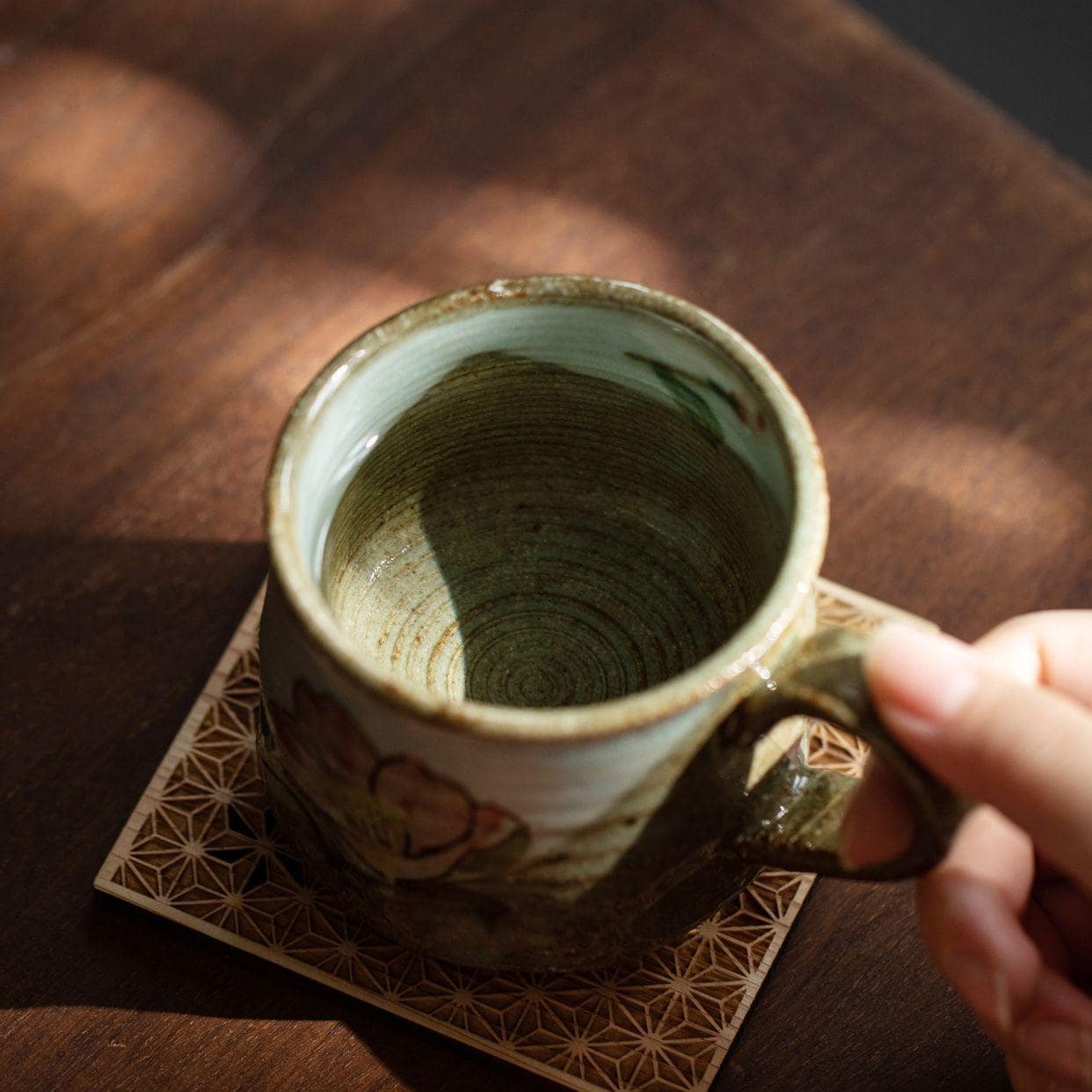 Pair of rustic animal-themed ceramic cups on a wooden table.