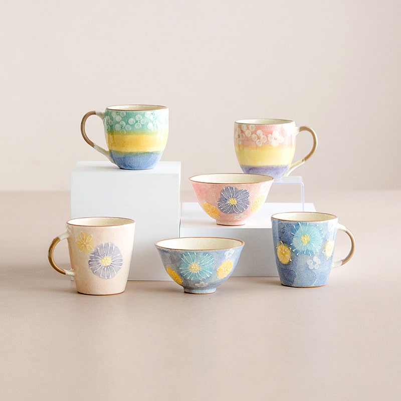 Pastel gradient ceramic cups with floral accents on display