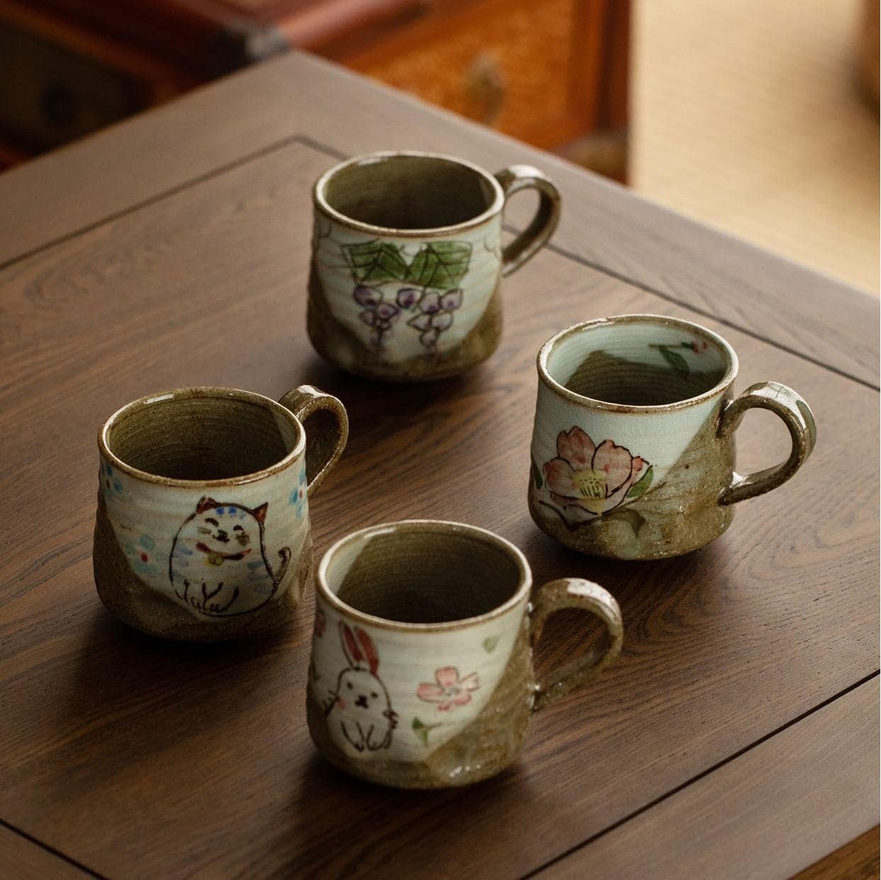 Collection of whimsical hand-painted cups with animal designs on a shelf.