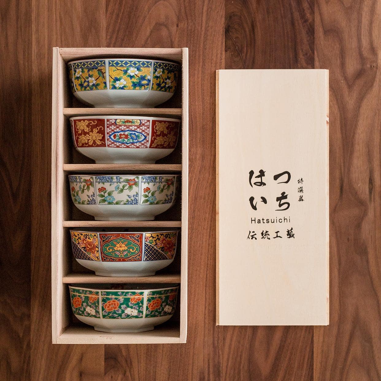 Vibrant red and gold patterned soup bowl on wooden table.