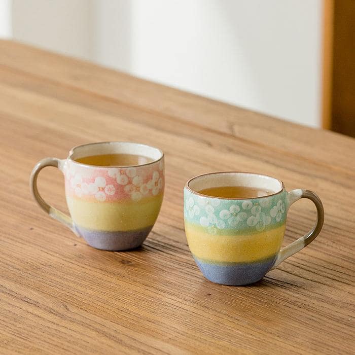 Hand-painted pastel ceramic cup with floral patterns on a wooden table