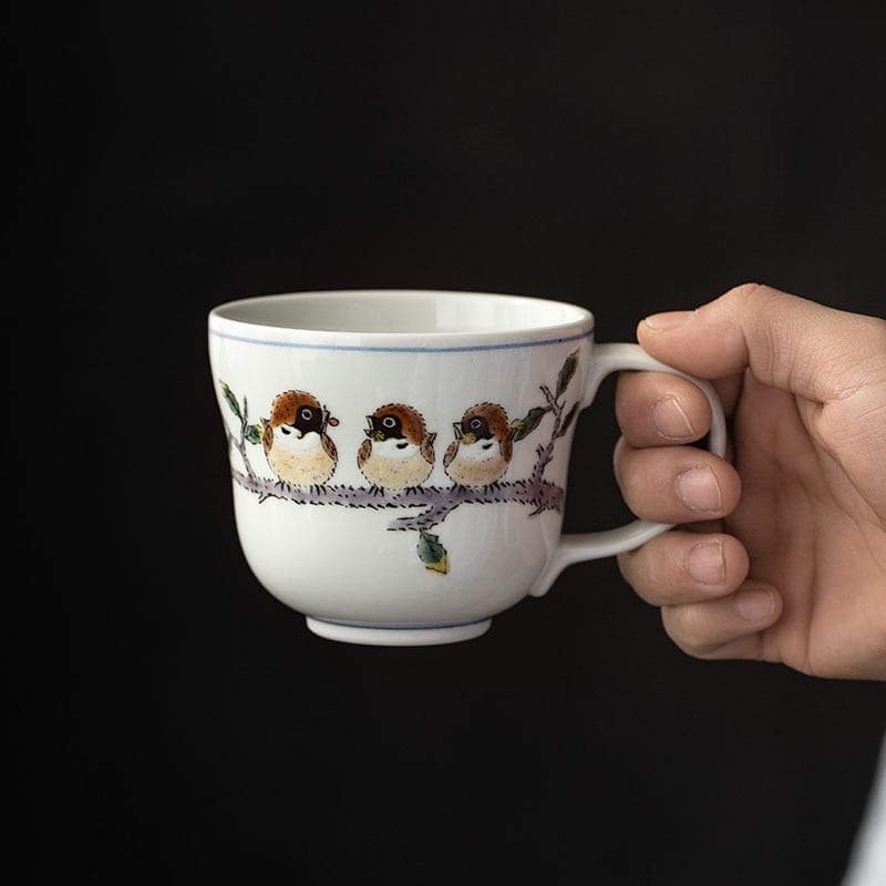 Sparrow-motif ceramic cup on a wooden table