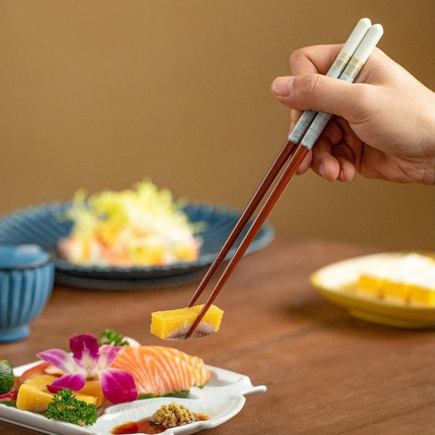 Elegant wooden chopsticks set paired with sushi and wooden rests.