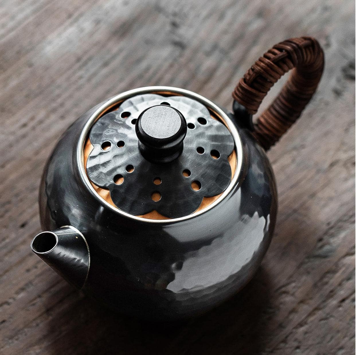 Hammered copper kettle with bamboo handle on a woven mat