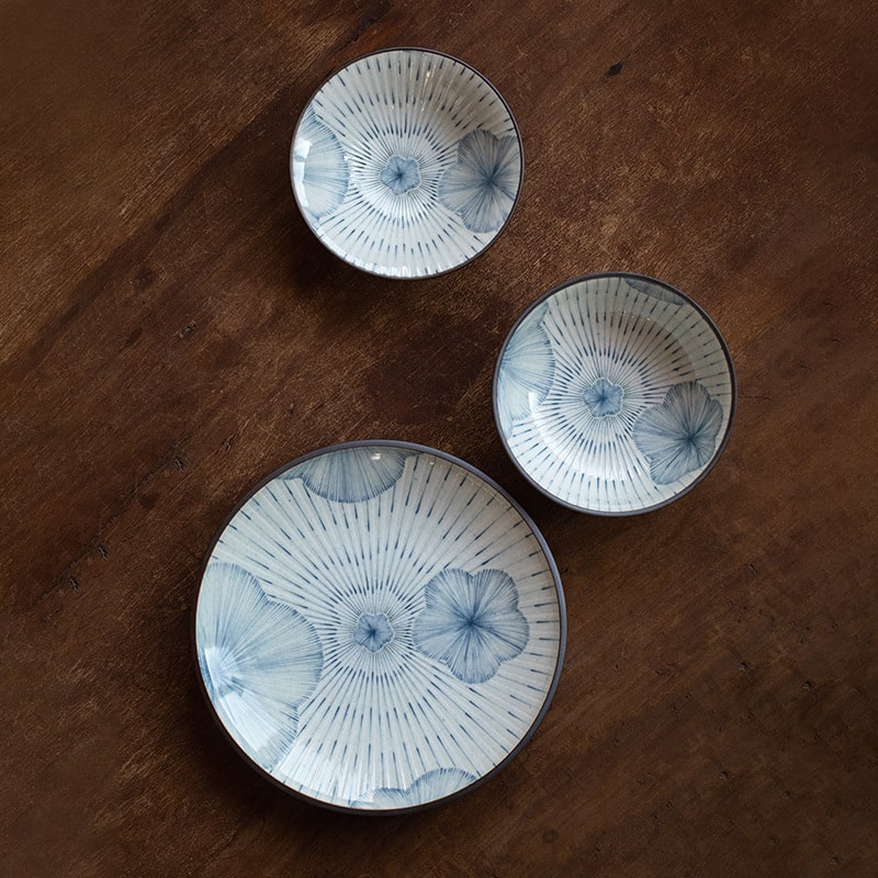 Handcrafted ceramic bowls and plates arranged on a wooden surface